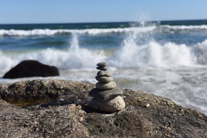 Stone cairn on boulder on the ocean shore.