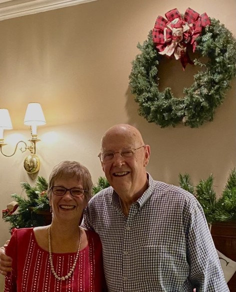 tom and his wife Dona, Christmas wreath on the wall