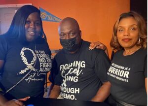 3 people together, wearing black t-shirts about fighting cancer